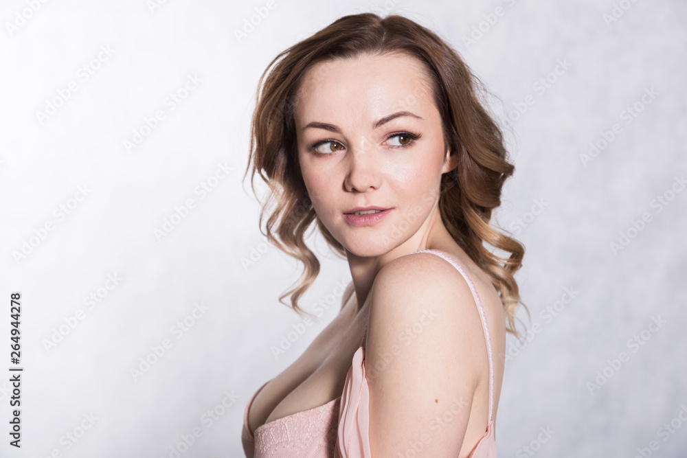 Portrait of beautiful young elegant female in pale pink wedding dress with big neckline, on a white background. Portrait of beautiful young elegant female in pale pink wedding dress with big neckline, on a white background.
