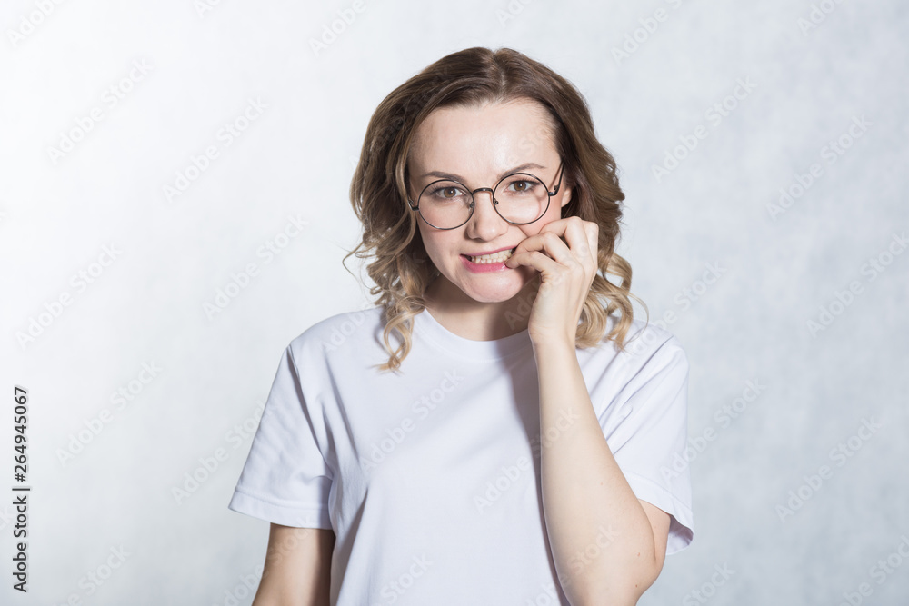 Beautiful young woman feels anxious, bites finger nails in confusion. Beautiful young woman feels anxious, bites finger nails in confusion.
