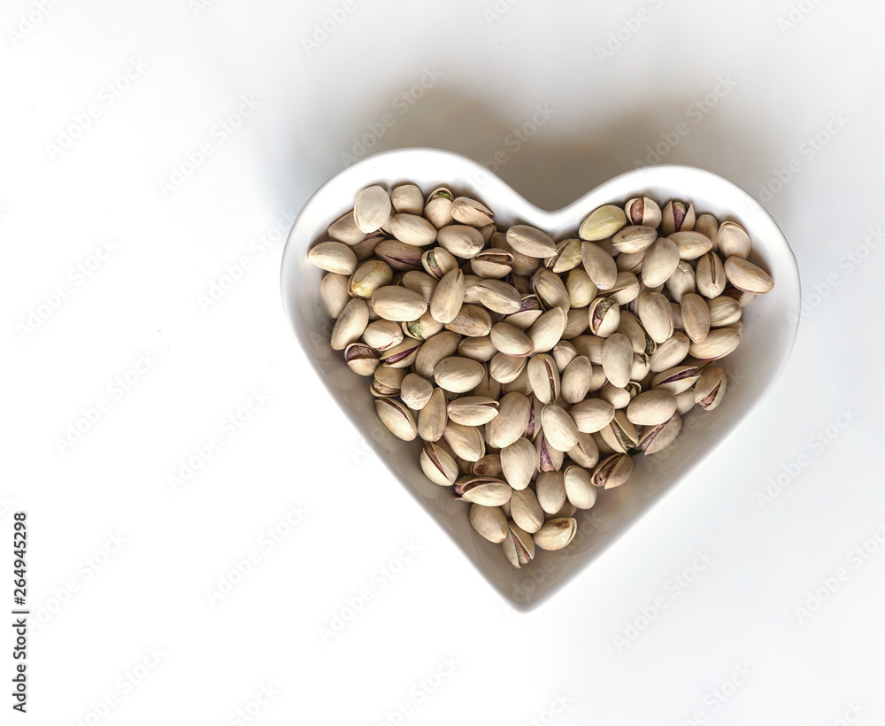 Nuts arranged in heart on background. Healthy Food image close up pistachios on the cup plate. Love Texture on white grey table top view mock up Nuts arranged in heart on background. Healthy Food image close up pistachios on the cup plate. Love Texture on white grey table top view mock up