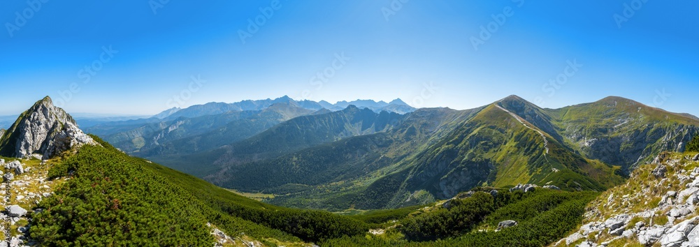 Extra wide panorama of High Tatra main ridge of mountains during summer with blue sky with clouds, Poland