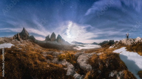 Panarama Mountain valley at beautiful night. Autumn landscape with mountains, hills, stones, grass, blue sky with clouds and moon at sunset. High rocks at dusk. Tre Cime park in Dolomites, Italy. 