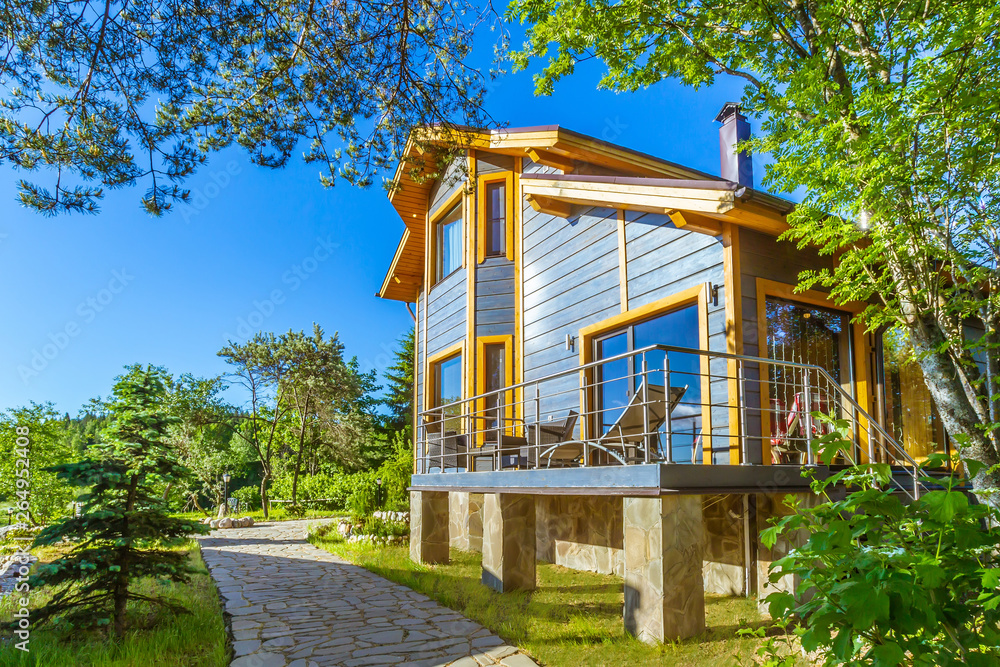 Two-storey country cottage. Villa with open veranda. Vacation resort. Comfortable cottage for family rest. Cottages for rent outside the city. Tourist base. Recreation. - obrazy, fototapety, plakaty 
