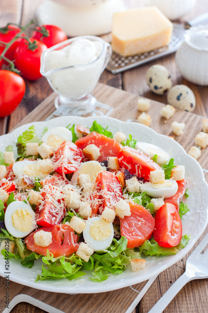 Caesar salad with salted salmon on a white plate, selective focus Caesar salad with salted salmon on a white plate, selective focus
