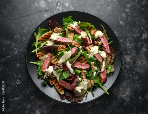 Grilled Beef Steak salad with pears, walnuts and greens vegetables and blue cheese sauce. healthy food.