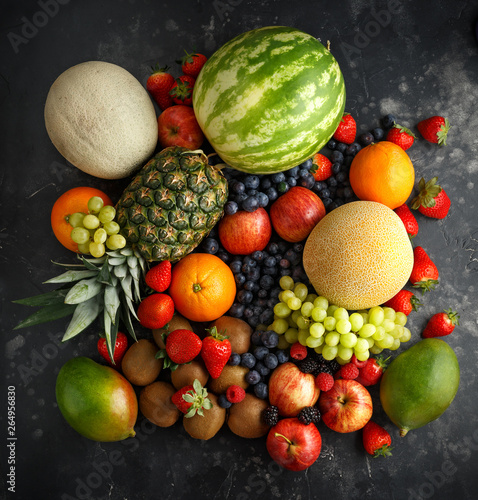 Variety of fresh fruits and berries on dark background  cantaloupe  melon  watermelon  blueberry  oranges  apple  strawberry  pineapple  mango  grapes and kiwi.