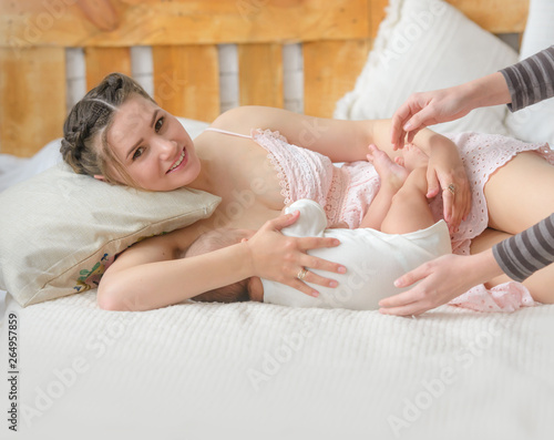 A young mother is feeding her baby. The lactation consultant helps her. Breastfeeding Concept 