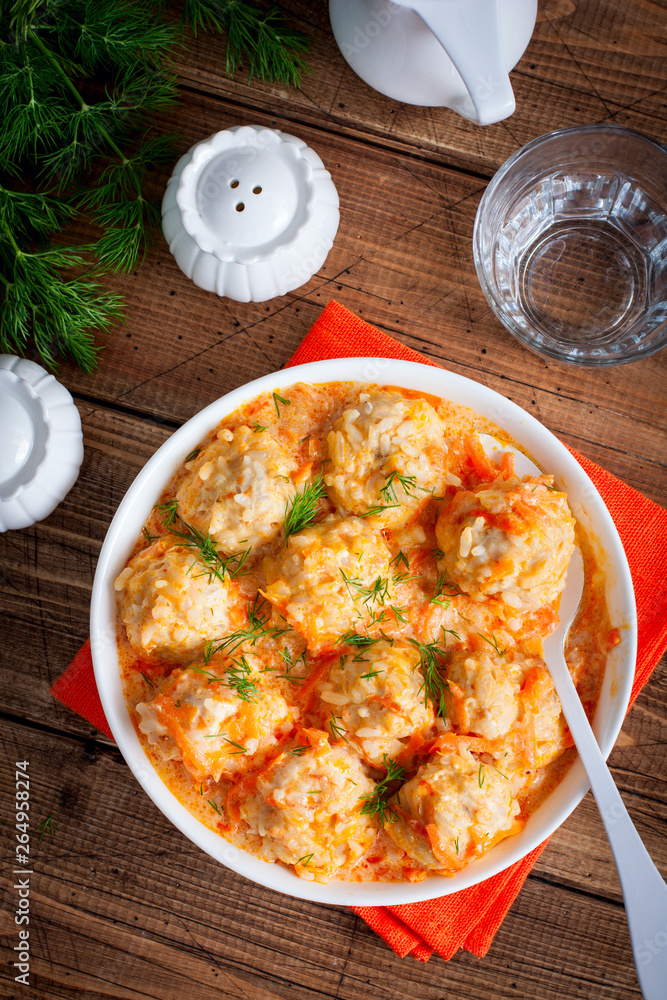 Meatballs with rice in tomato-sour cream sauce on a wooden table, top view, selective focus Meatballs with rice in tomato-sour cream sauce on a wooden table, top view, selective focus