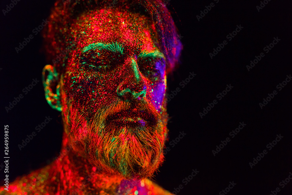 Concept. Portrait of a bearded man. The man is painted in ultraviolet powder. Concept. Portrait of a bearded man. The man is painted in ultraviolet powder.