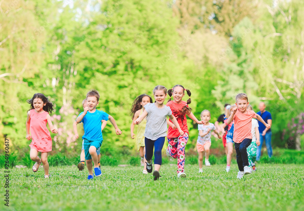 Many different kids, boys and girls running in the park on sunny summer day in casual clothes Many different kids, boys and girls running in the park on sunny summer day in casual clothes