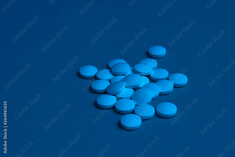 White pills with blue neon lights closeup