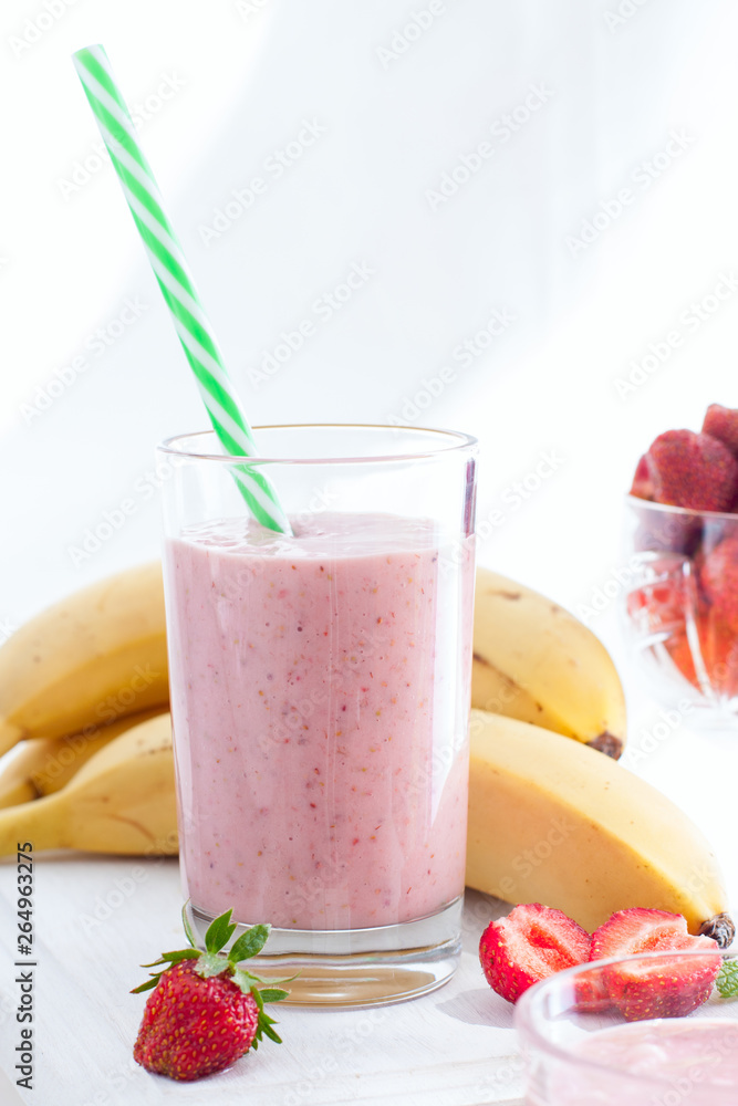 Smoothies of strawberries and bananas in glass glasses on a white table, selective focus Smoothies of strawberries and bananas in glass glasses on a white table, selective focus