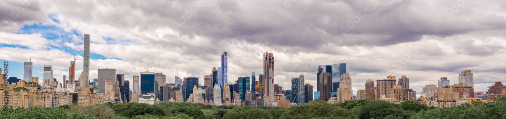 The beautiful New York City skyline with an interesting cloudy sky behind. Panorama of full skyline with all the famous towers and buildings.