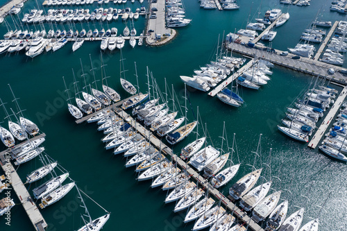 Aerial view of a lot of white boats and yachts moored in marina. Photo made by drone from above.