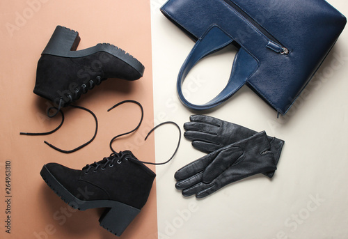 Fashionable women's shoes and accessories on beige brown background. Black boots, leather gloves, bag. Top view. Flat lay