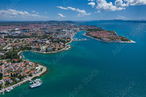 Aerial view of city of Zadar. Summer time in Dalmatia region of Croatia. Coastline and turquoise water and blue sky with clouds. Photo made by drone from above.