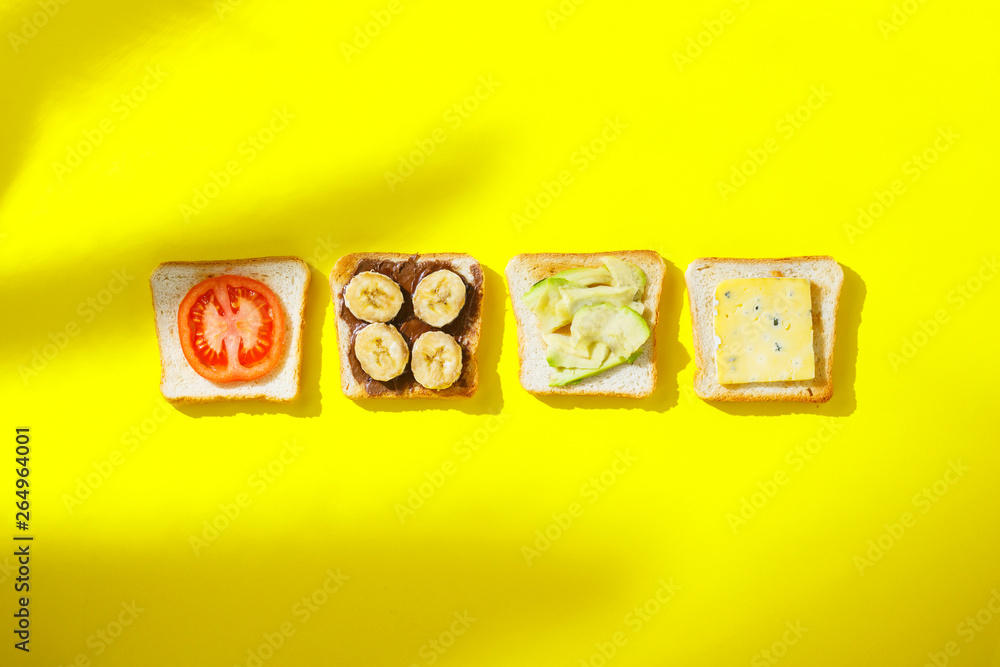 Sandwiches with banana, tomato, avocado, blue cheese on a yellow background. Concept of a healthy breakfast, vitamins, proper nutrition. Natural light, shade from plants. Flat lay, Top view.