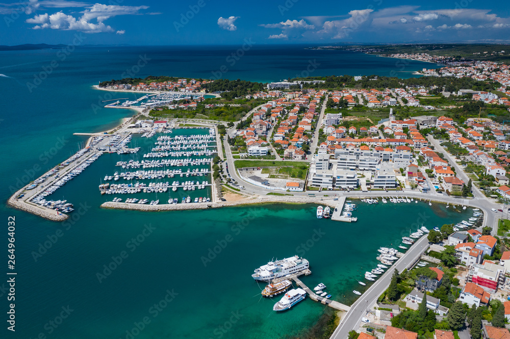 Fototapeta premium Aerial view of city of Zadar. Summer time in Dalmatia region of Croatia. Coastline and turquoise water and blue sky with clouds. Photo made by drone from above.