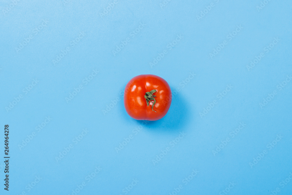 Tomato on a blue background. Concept of vitamins, summertime, breakfast. Flat lay, top view. Tomato on a blue background. Concept of vitamins, summertime, breakfast. Flat lay, top view.