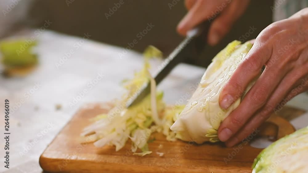 Woman cutting cabbage on kitchen table close up Woman cutting cabbage on kitchen table close up