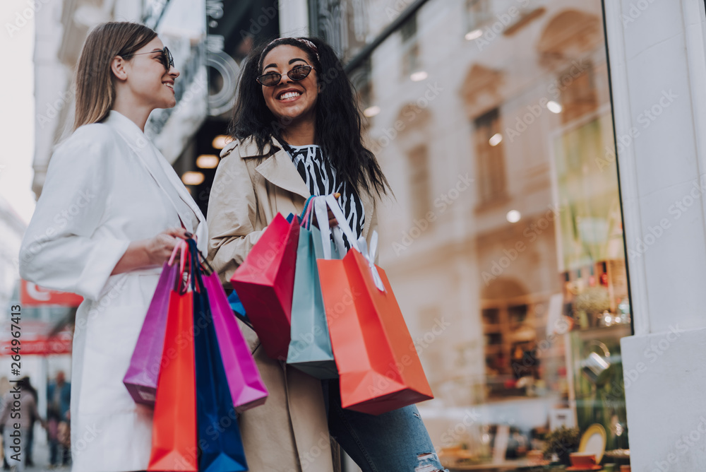 Two beautiful cheerful women with shopping bags standing on the street Two beautiful cheerful women with shopping bags standing on the street