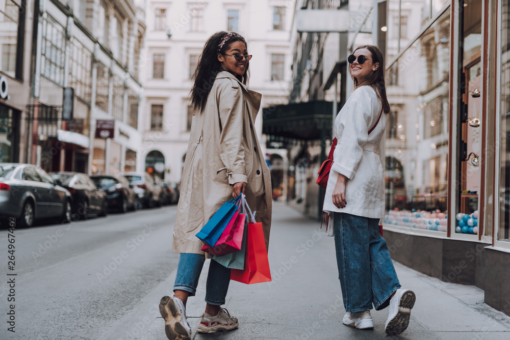 Two beautiful young women with shopping bags walking on the street