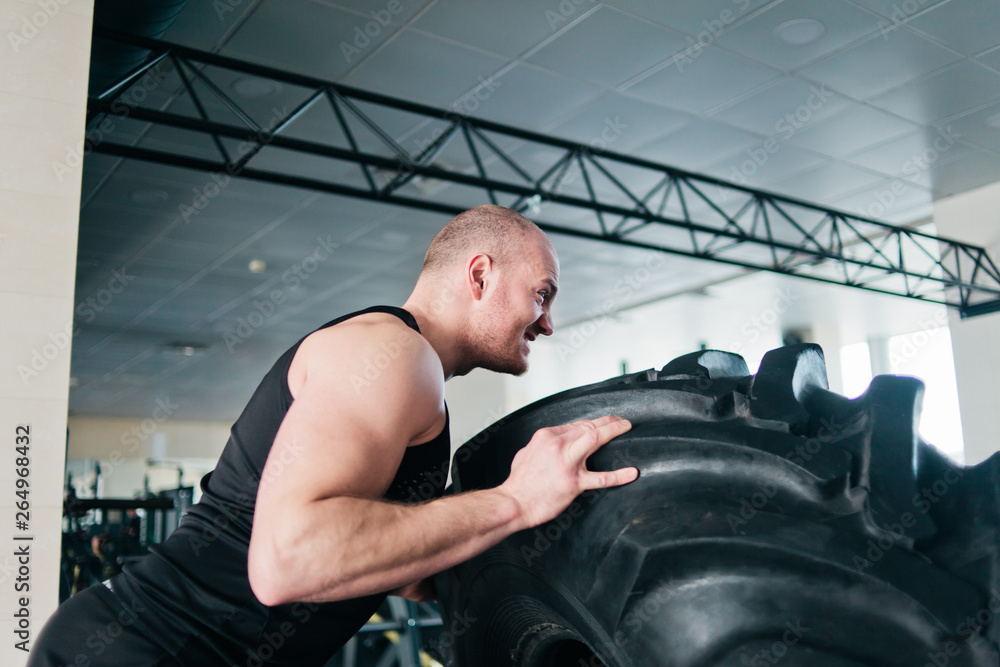 Powerful man is pushing a big heavy rubber wheel. Functional training Powerful man is pushing a big heavy rubber wheel. Functional training