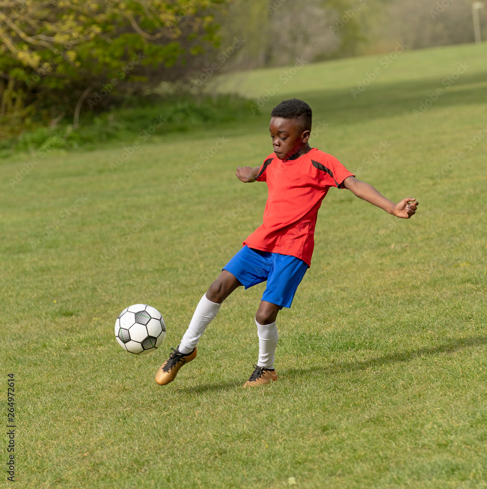 Hampshire, England, UK. April 2019. A nine year old footballer dribbles the soccer ball during a training session in a public park. Hampshire, England, UK. April 2019. A nine year old footballer dribbles the soccer ball during a training session in a public park.
