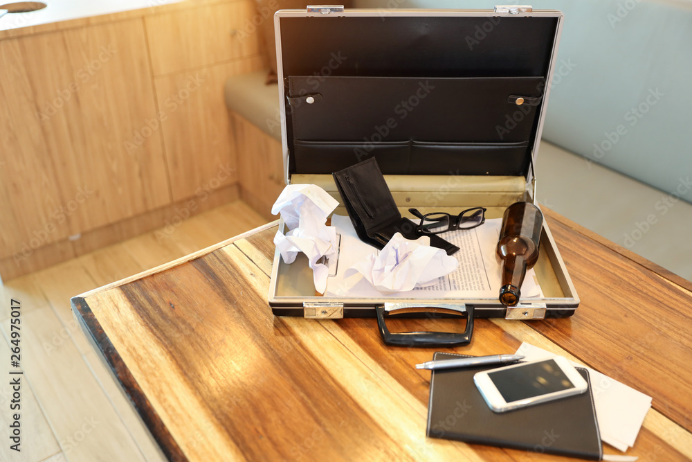 business bag with empty wallet, alcohol bottle and paper garbage on wood table business bag with empty wallet, alcohol bottle and paper garbage on wood table