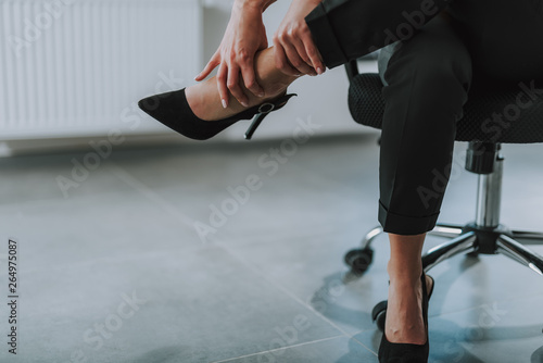 Woman touching her leg after tiresome working day