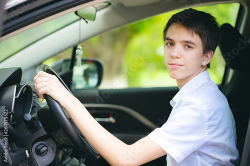 happy teenager got a driver's license and sits behind the wheel of a car