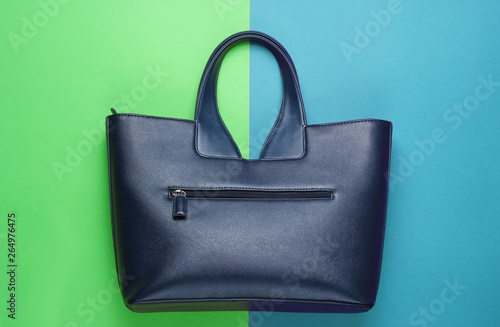 Leather handbag on green-blue background. Top view