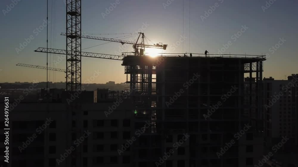 Construction Site at sunset. Silhouette of a construction crane near the building Construction Site at sunset. Silhouette of a construction crane near the building