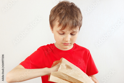 Young cut boy take out something from a paper package on a white background.