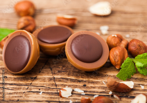 Box of homemade candies on wooden background with mint and nuts. A hazelnut in Caramel and chocolate. photo