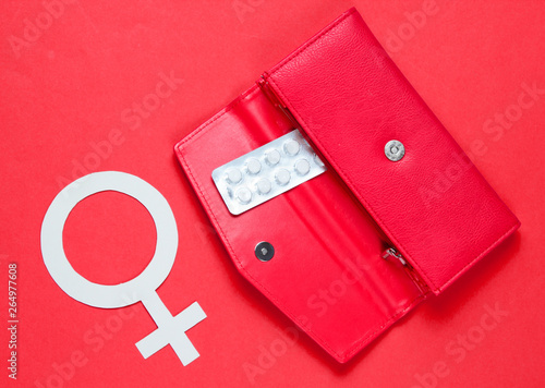 Women Health. Female gender symbol  pills in red purse on red background.