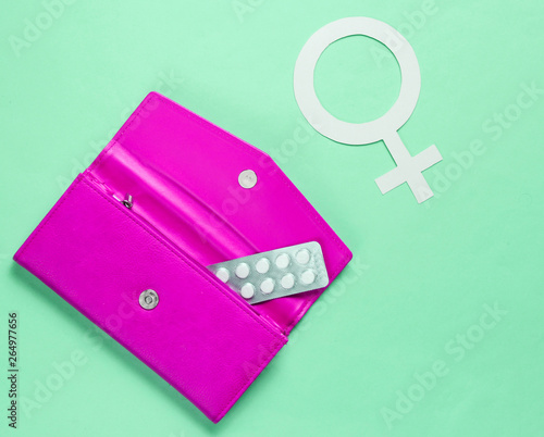 Women Health. Female gender symbol, pills in pink purse on green background. photo