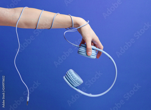 Hand wrapped cable holds blue headphones on blue background