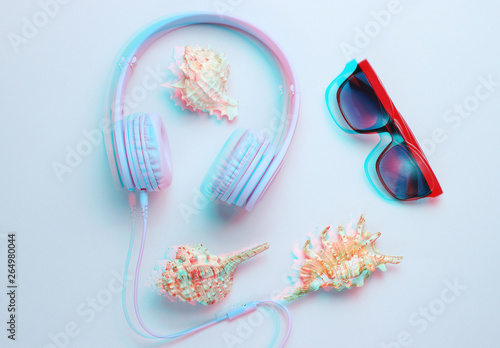 Headphones, sunglasses, shells on gray background. Beach music. Top view. Glitch effect