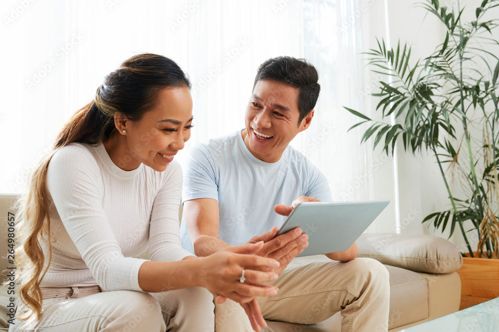Cheerful couple watching show on tablet computer Cheerful couple watching show on tablet computer