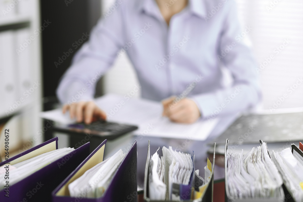 Bookkeeper woman or financial inspector making report, calculating or checking balance, close-up. Business, audit or tax concepts Bookkeeper woman or financial inspector making report, calculating or checking balance, close-up. Business, audit or tax concepts