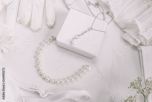 White bridal accessories for wedding background with pearls, white satin ribbons and lace, gloves, bracelet,flat lay for fashion blog, top view