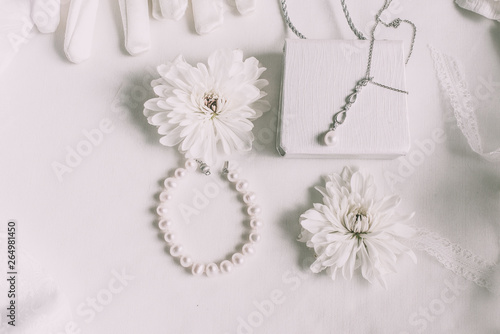 White bridal accessories for wedding background with pearls, white satin ribbons and lace, gloves, bracelet,flat lay for fashion blog, top view