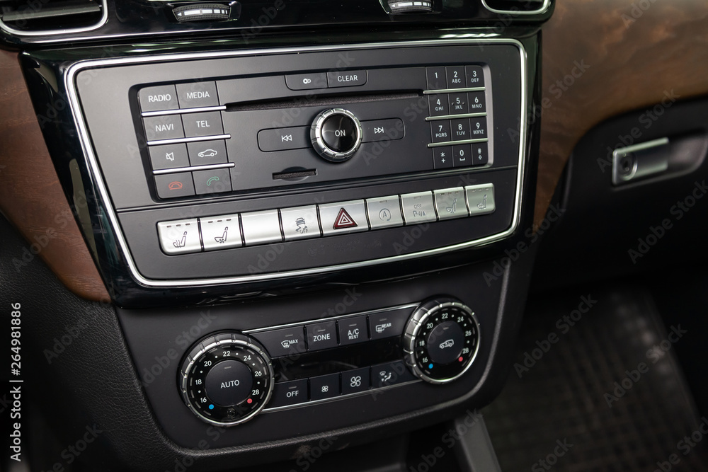 The central control console on the panel inside the car close-up with climate control and audio system and a hole for the CD and emergency button in gray and black. Auto service industry. Comfort. The central control console on the panel inside the car close-up with climate control and audio system and a hole for the CD and emergency button in gray and black. Auto service industry. Comfort.
