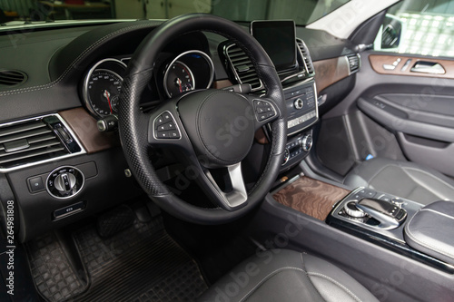 View to the black color interior of suv car with front seats, steering wheel and dashboard  with gray leather upholstery after cleaning and detailing in vehicle repair workshop. Auto service industry. © Aleksandr Kondratov
