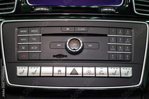 The central control console on the panel inside the car close-up with climate control and audio system and a hole for the CD and emergency button in gray and black. Auto service industry. Comfort.