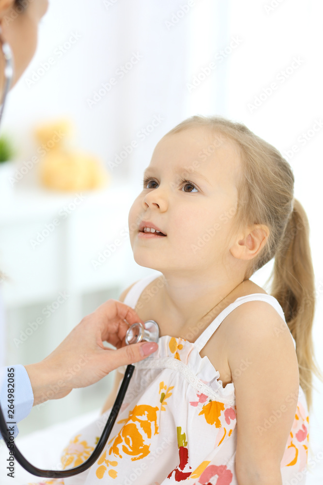 Doctor examining a little girl by stethoscope. Happy smiling child patient at usual medical inspection. Medicine and healthcare concepts Doctor examining a little girl by stethoscope. Happy smiling child patient at usual medical inspection. Medicine and healthcare concepts