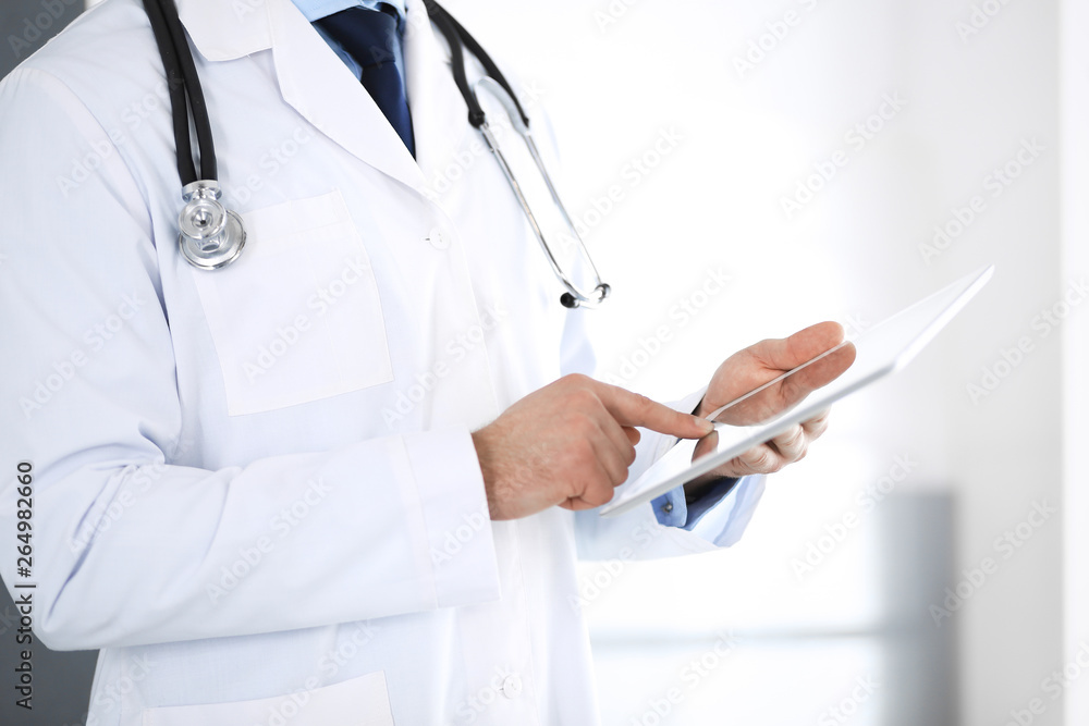 Doctor man using tablet computer for network research or virtual disease treatment, hands close-up. Perfect medical service in clinic. Modern medicine, medic data and healthcare concepts Doctor man using tablet computer for network research or virtual disease treatment, hands close-up. Perfect medical service in clinic. Modern medicine, medic data and healthcare concepts