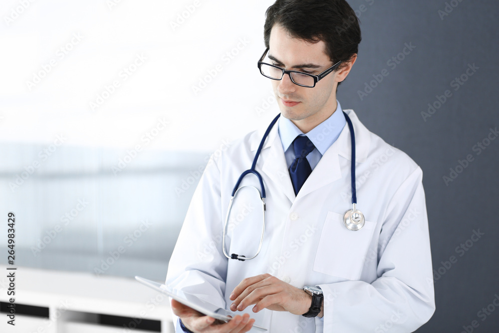 Doctor man using tablet computer for network research or virtual disease treatment. Perfect medical service in clinic. Modern medicine, medic data and healthcare concepts Doctor man using tablet computer for network research or virtual disease treatment. Perfect medical service in clinic. Modern medicine, medic data and healthcare concepts