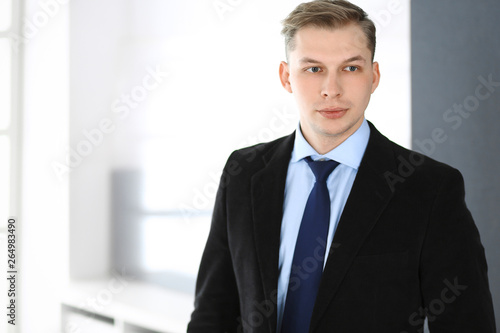 Headshot of businessman standing straight in office. Success and business workplace concept