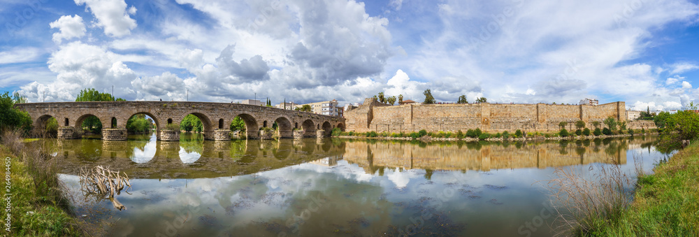 Fototapeta premium View of the Roman bridge of Merida with its reflection on the Guadiana river. Merida. Spain.The Archaeological Ensemble of Merida is declared a UNESCO World Heritage Site Ref 664. Panorama image from